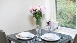 Une table dressée avec des assiettes, des couverts et un vase de fleurs.