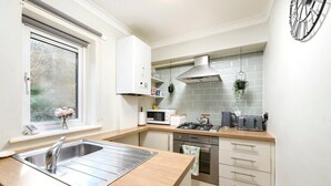 Une cuisine de taille réduite équipée d’un évier, d’une cuisinière, d’un four à micro-ondes et de placards.