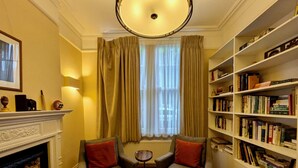 A cozy reading room with two armchairs, a fireplace, and a bookshelf filled with books. - Stunning Family Home in Tulse Hill (London)