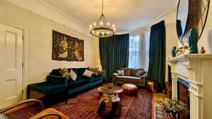 A traditional living room with a green sofa, a patterned rug, and a fireplace. - Stunning Family Home in Tulse Hill (London)