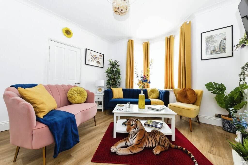 A living room with a sofa, armchair, coffee table, and a tiger statue.