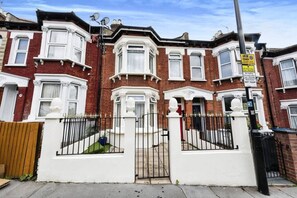 A row of red brick terraced houses with white window frames and a gated entrance.