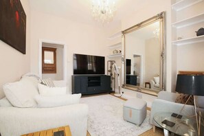 A living room with a large mirror, a television, and a sofa.
