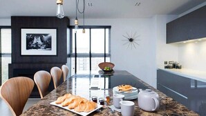 Uma cozinha moderna com bancada de mármore, uma mesa de jantar com cadeiras e um quadro pendurado na parede.
