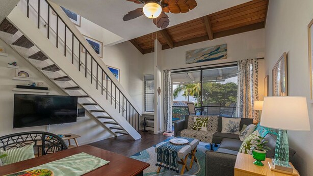 A spacious living area with a wooden staircase, a dining table, and a comfortable seating arrangement.