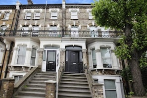 Traditional house with a central entrance, decorative brickwork, and a balcony on the upper floor.