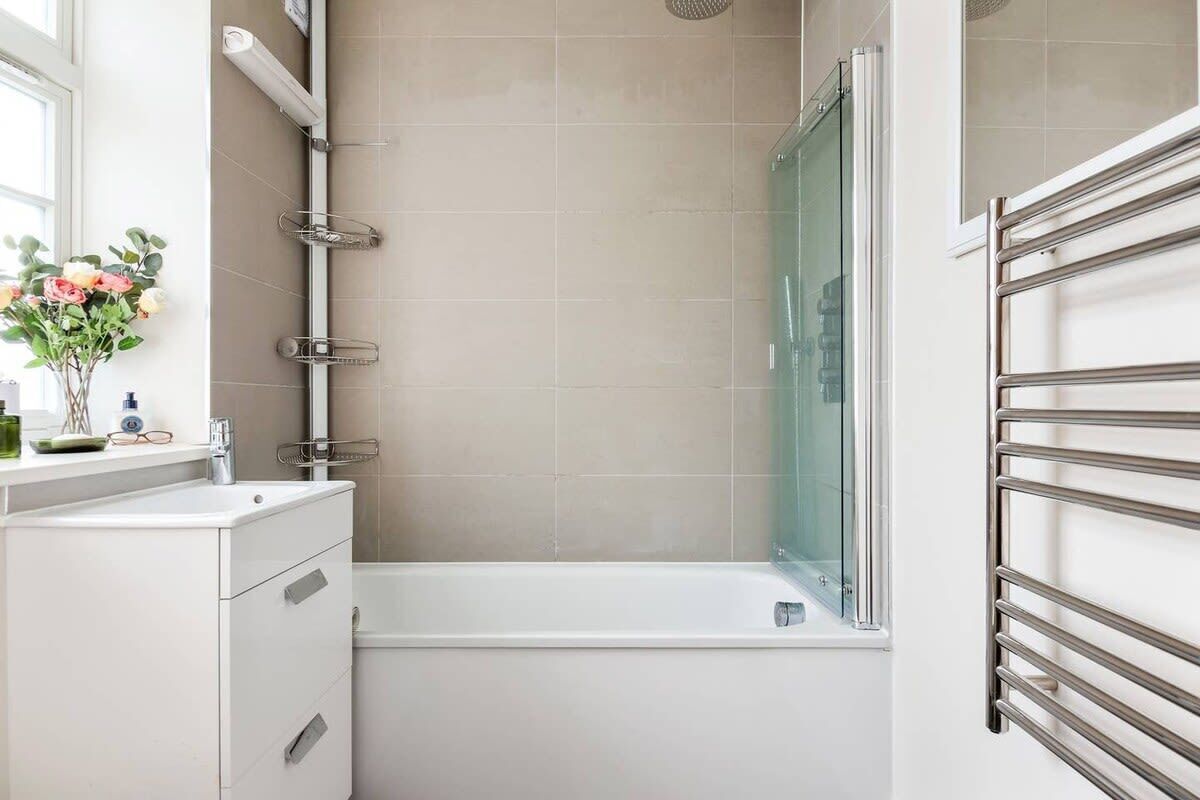 A modern bathroom with a shower, a glass-enclosed bathtub, and a white vanity with drawers.