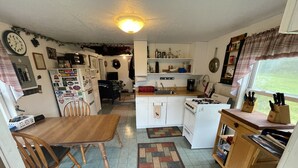 Une cuisine compacte comprenant une table à manger, des chaises, un réfrigérateur, une cuisinière et une fenêtre donnant sur un paysage agréable.