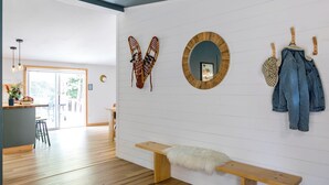 Un interior moderno con un banco de madera, un espejo en la pared y un par de esquíes.