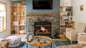 Una sala de estar con chimenea de piedra, estantes de madera, un televisor y un rincón de descanso acogedor.