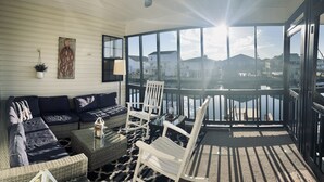 A sunlit balcony with a view of a marina, furnished with a sofa, chairs, and a table. - Waterfront Beach House on the Canal with Deep Water Access to Ocean w/Boat Ramp. (North Myrtle Beach)