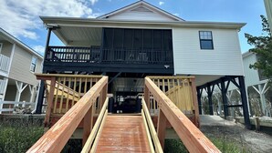 A two-story house with a balcony and a wooden deck. - Waterfront Beach House on the Canal with Deep Water Access to Ocean w/Boat Ramp. (North Myrtle Beach)