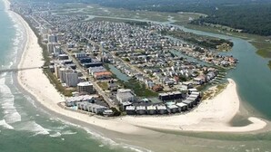 An aerial view of a coastal town with a beach, residential buildings, and a bridge. - Waterfront Beach House on the Canal with Deep Water Access to Ocean w/Boat Ramp. (North Myrtle Beach)