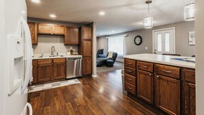 A kitchen with wooden cabinets, a white refrigerator, and a large island with drawers.