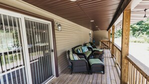 A covered porch with wicker furniture and a sliding glass door.