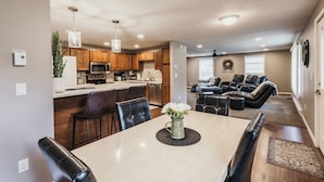 A spacious living area with a dining table, leather chairs, a sofa, and a fireplace.