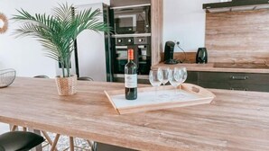 Een keuken met een houten aanrecht, een bloempot, een wijnfles en drie wijnglazen.