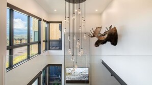 Um interior moderno com grandes janelas, uma cabeça de veado montada e um lustre.