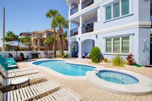 Un área de piscina con sillones reclinables, una bañera de hidromasaje y un patio con mobiliario exterior.