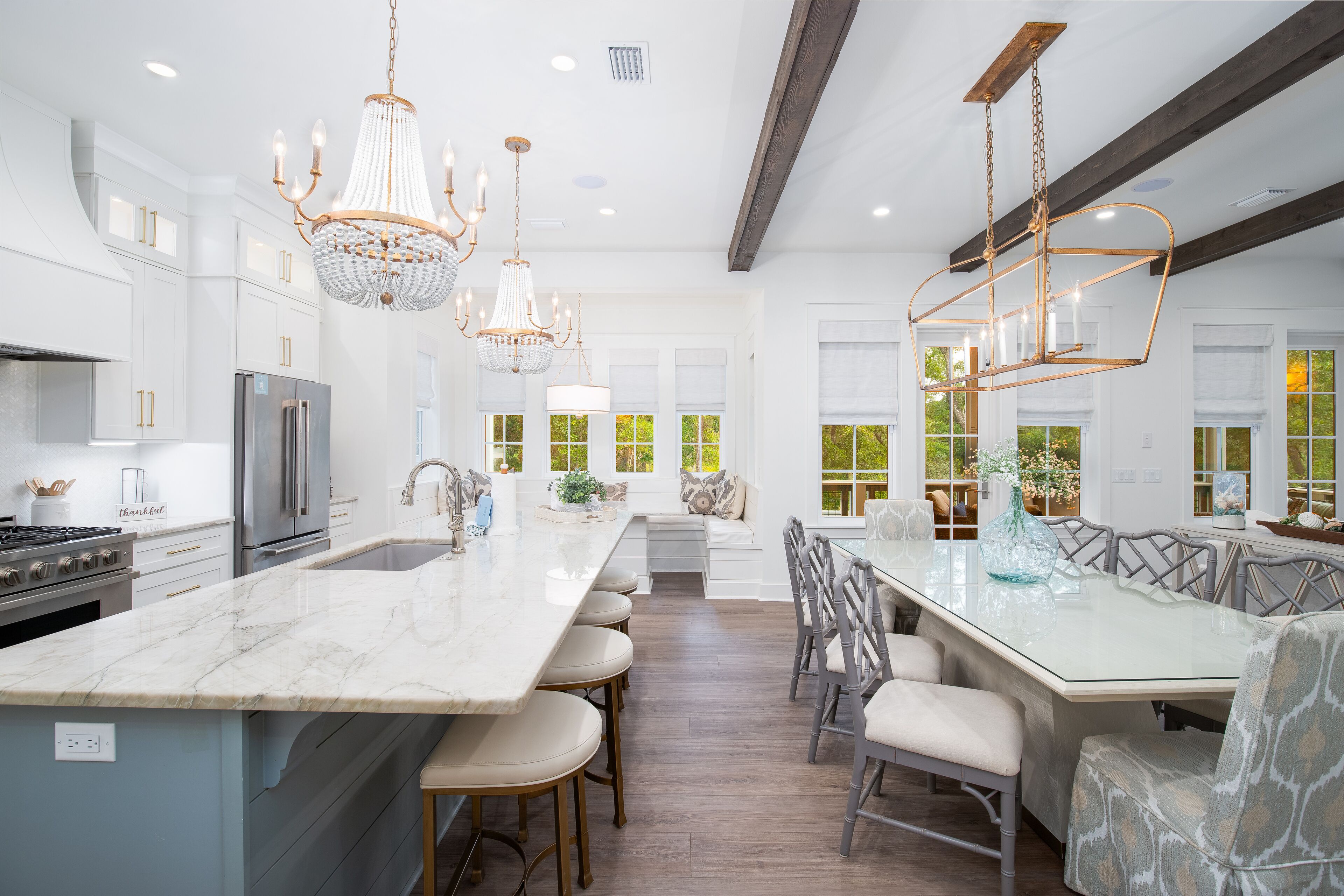 A modern kitchen with a large island, stainless steel appliances, and a chandelier.