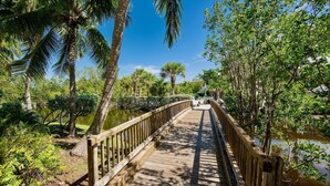 A wooden bridge over a body of water, surrounded by lush greenery and palm trees. - **THE OSPREY'S NEST** Condo & Pool + Last Key White Glove Service... (Key West)