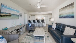 A modern living room with a sofa, coffee table, and a dining area with chairs. - **THE OSPREY'S NEST** Condo & Pool + Last Key White Glove Service... (Key West)