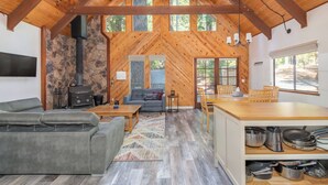 Een gezellig cabin interieur met een stenen muur, een open haard, een bank, een eettafel en een keukenhoek.