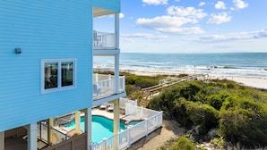 Ein zweistöckiges Gebäude mit Pool und Blick auf den Strand.
