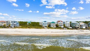 Ein Strandhotel mit mehreren Gebäuden, einem Sandstrand und Wellen.