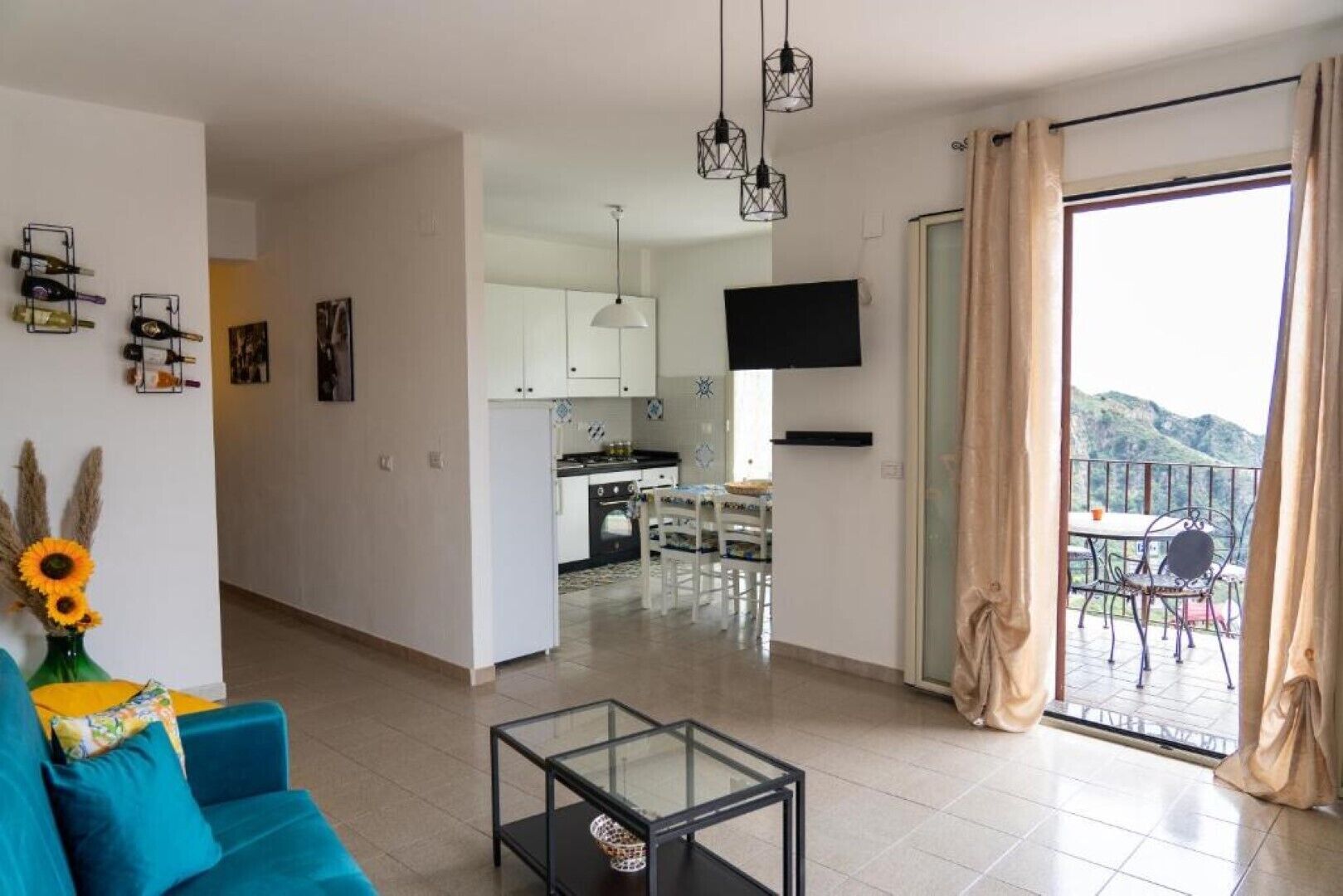 A modern living room with a sofa, a glass coffee table, and a kitchen in the background.