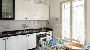 A kitchen with white cabinets, a black countertop, and a patterned tablecloth. - Mirador Savoca (Savoca)