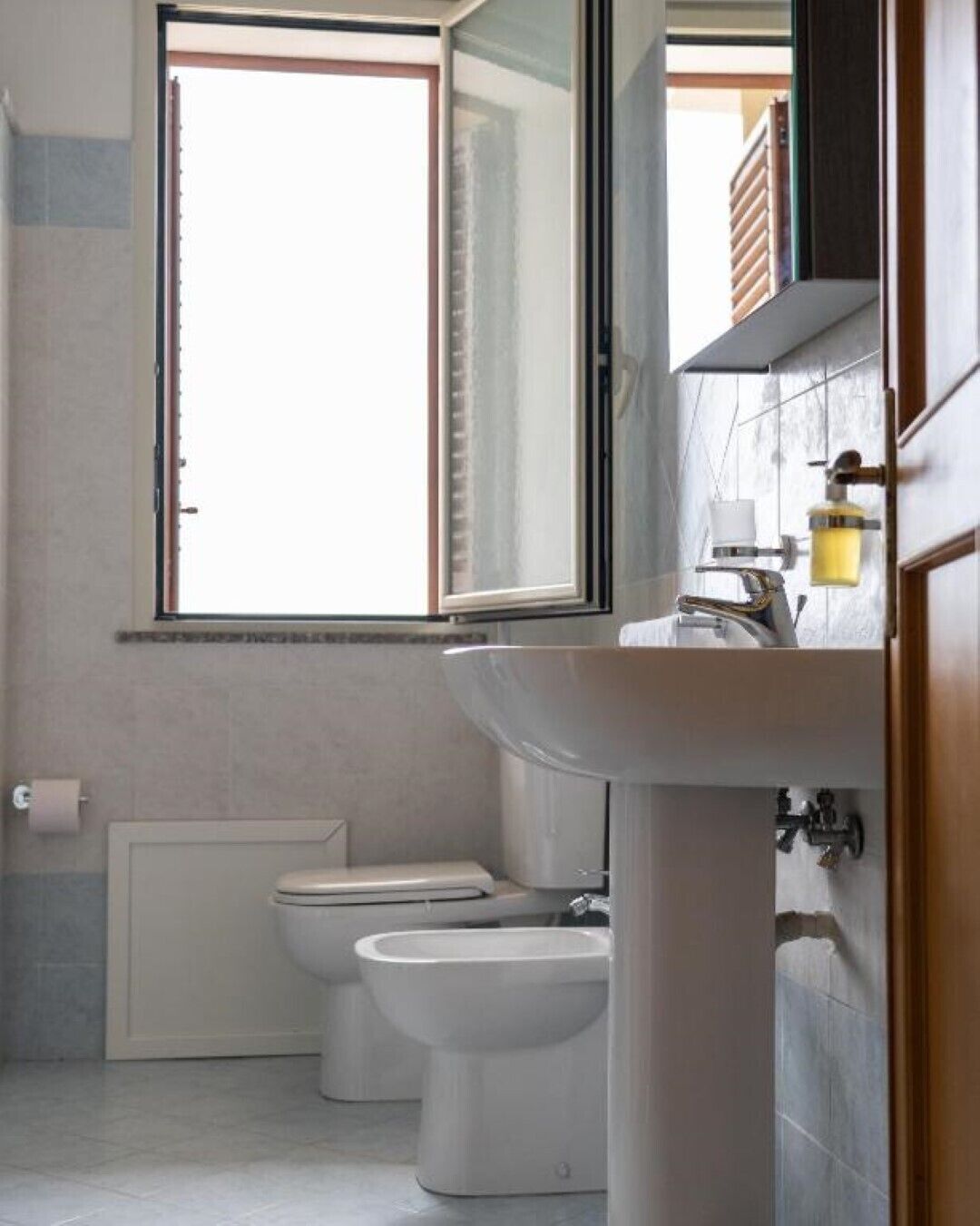 A bathroom with a toilet, bidet, and sink.