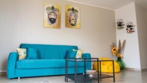 A living room with a blue sofa, a coffee table, and two wall-mounted artworks. - Mirador Savoca (Savoca)