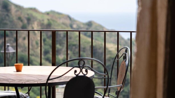 A balcony with a table and chairs, overlooking a mountainous landscape. - Mirador Savoca (Savoca)