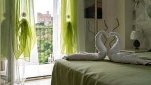 A hotel room with a bed, a view of greenery outside, and a painting on the wall. - Mirador Savoca (Savoca)