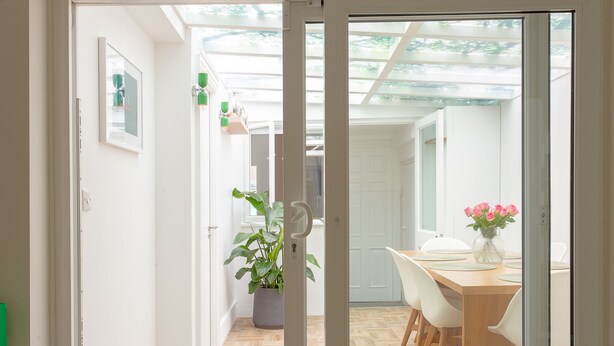 A modern interior with a wooden dining table, white chairs, a potted plant, and a vase with flowers. - Cosy Gem in Covent Garden (London)