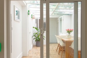 A modern interior with a wooden dining table, white chairs, a potted plant, and a vase with flowers. - Cosy Gem in Covent Garden (London)