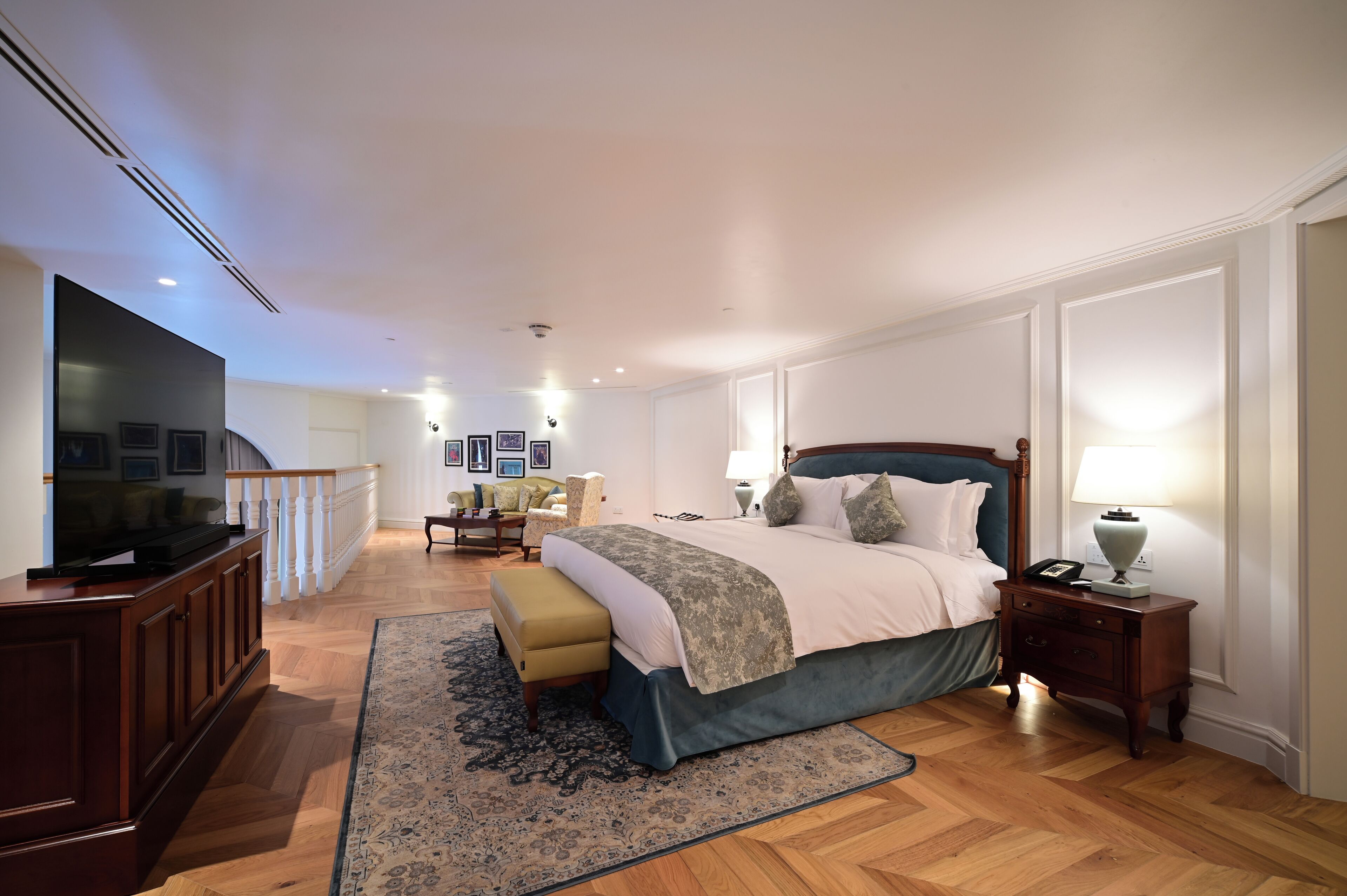 A spacious bedroom with a large bed, a television, a nightstand, and a wooden floor.