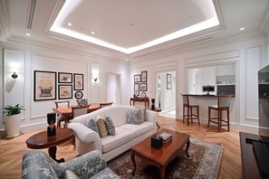 A spacious living room with a sofa, coffee table, and chairs, a dining area with a table and chairs, and a kitchen area with bar stools. - 21 High Street Residence By The Torch (Doha)