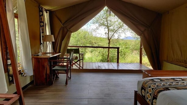 Een tent met een bed, een bureau en een stoel.