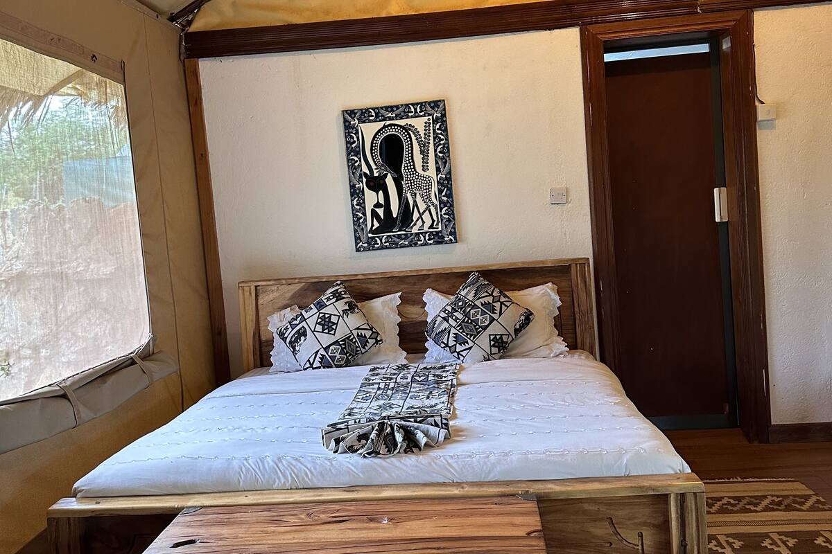 A tent-style room with a bed, wooden headboard, and a decorative wall hanging.