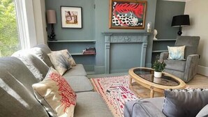 Een woonkamer met een zithoek, een salontafel, een schaakbord en een open haard.