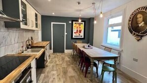 Een moderne keuken met een houten aanrecht, een eethoek met een houten tafel en stoelen, en een portret aan de muur.