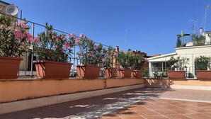 A rooftop terrace with terracotta tiles, potted plants, and a clear blue sky. - Little Aventino BnB - in the heart of Rome (Roma)