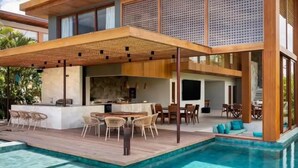 Una casa moderna con piscina, mobiliario de exterior y un porche cubierto.
