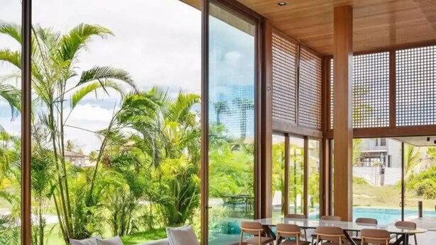 Un interior moderno con un amplio ventanal, una piscina y techo de madera.