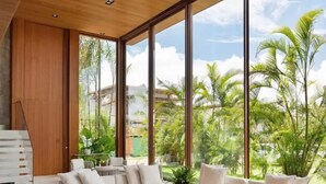 Una sala de estar moderna con un gran ventanal, un sofá blanco y una mesa de centro de madera.