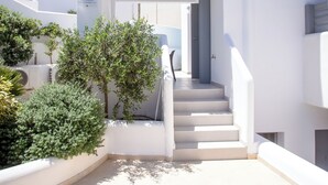 A white building with a staircase leading to a door, surrounded by greenery and a clear sky. - Whisper Villa Mykonos (Mykonos)