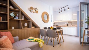A modern living room with a sofa, dining area, kitchen, and a staircase. - Whisper Villa Mykonos (Mykonos)