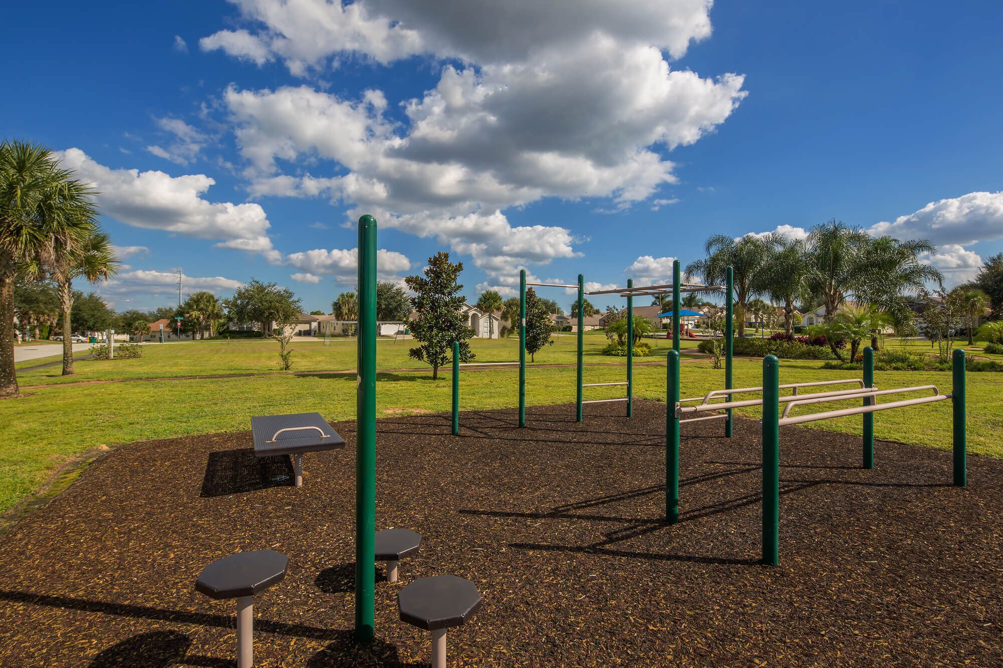 An outdoor exercise area with a rubberized floor, exercise equipment, and seating.